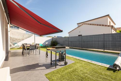 un patio avec un grill et une table à côté d'une piscine dans l'établissement Ô Soleil - Avec piscine privée, à Vendres