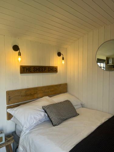 a bed in a room with a sign on the wall at Shepherds Huts in Kidlington