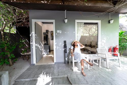 a woman sitting on a chair outside a house at Tropical Tree in Fehendhoo