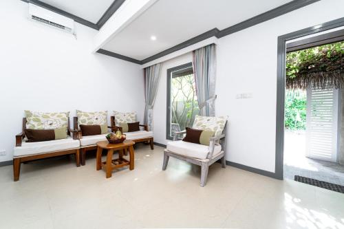 a living room with white furniture and windows at Tropical Tree in Fehendhoo