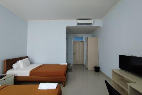 a hotel room with two beds and a flat screen tv at Hotel Sutha Inn in Jambi