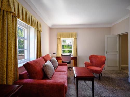 a living room with a red couch and two chairs at Delta Hotels by Marriott Breadsall Priory Country Club in Derby
