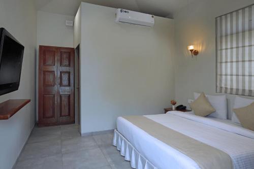 a bedroom with a bed and a television and a door at juSTa Rudra Resort & Spa in Kolād