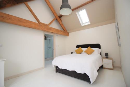 GantonにあるCountry Retreat, Barn Conversion, Dog friendlyの白い壁と木製の梁のベッド付きのベッドルーム1室