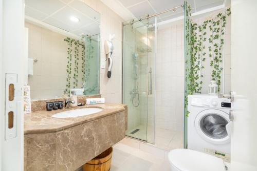 a bathroom with a sink and a washing machine at Cozy Haven with Spiritual Charm in JLT in Dubai