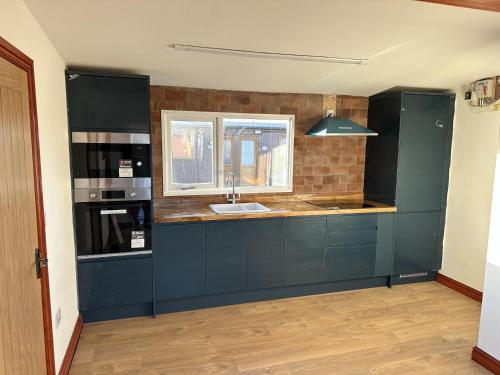 a kitchen with blue cabinets and a sink and a window at 2BR-Sleeps3-Parking-NearBeach in Mablethorpe