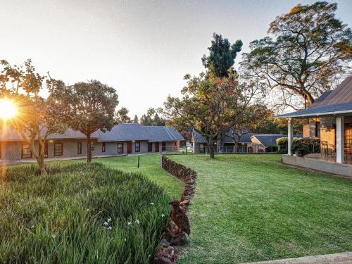 a yard with a stone wall and a house at The Peech Boutique Hotel Zimbabwe in Kingsmead
