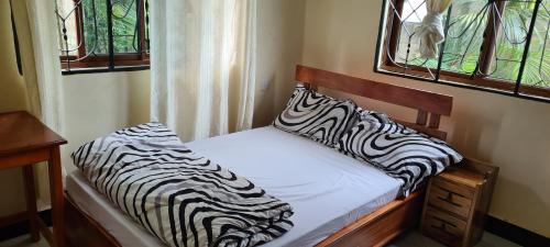 a bed with zebra pillows on it in a room at Triple D's in Moshi