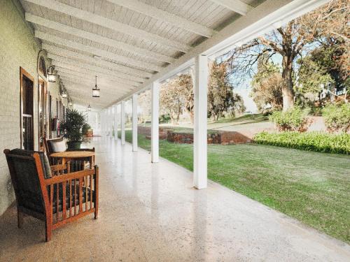 a covered porch with a bench and a lawn at The Peech Boutique Hotel Zimbabwe in Kingsmead
