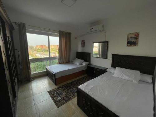 a bedroom with two beds and a large window at شالية مارينا وادى دجلة in Ain Sokhna