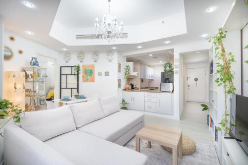 a living room with a white couch and a table at Cozy Haven with Spiritual Charm in JLT in Dubai