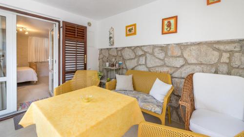 a living room with a table and chairs and a stone wall at Apartments Nadica in Baška
