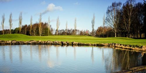 a golf course with a pond in front of a green at Escape Ordinary at Castle Hume in Enniskillen