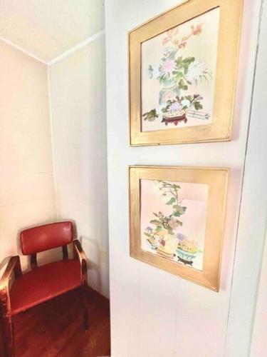 a red chair and two pictures on a wall at Humble Bee Cottage-Cullman in Hanceville