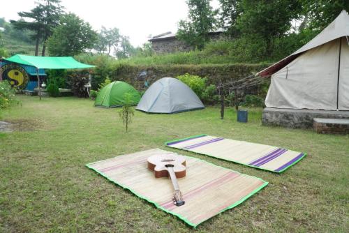a group of tents and a pair of scissors on a field at Shakoon Camps & Farmstay Nainital in Nainital