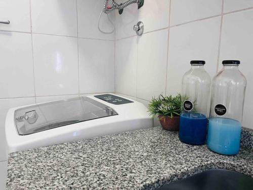 a kitchen counter with a sink and two glass bottles at Luminoso departamento con cochera in San Juan