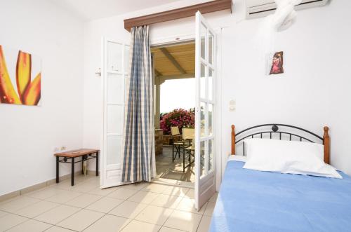 a bedroom with a bed and a door leading to a patio at Ydreos Studios & Apartments in Mikri Vigla