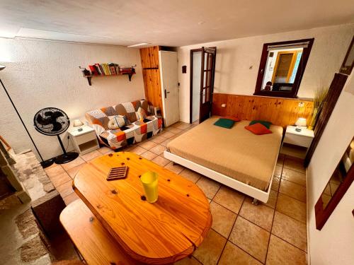 Cette chambre comprend un lit, une table et un canapé. dans l'établissement Casa Jeannot typique Corse en pierre, Location de SAMEDI EN SAMEDI , 2 pers, f2, 35 m2, jardin 60m2 vue montagne, parking, à Monacia-dʼAullène