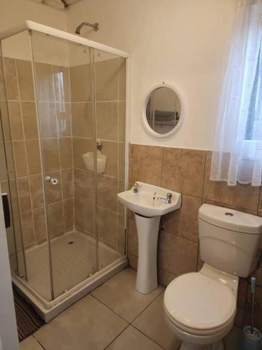 a bathroom with a shower and a toilet and a sink at Tenlet guesthouse in Pretoria