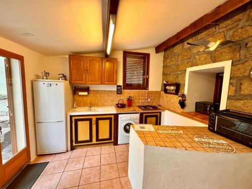 - une cuisine avec des appareils blancs et un mur en pierre dans l'établissement Casa Jeannot typique Corse en pierre, Location de SAMEDI EN SAMEDI , 2 pers, f2, 35 m2, jardin 60m2 vue montagne, parking, à Monacia-dʼAullène