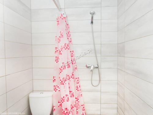 a bathroom with a shower with a pink shower curtain at Pod Akacją in Rewal