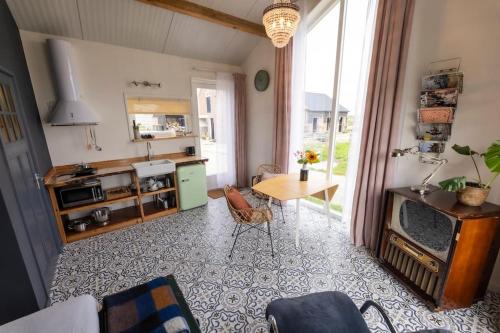 a living room with a kitchen and a table at De Boterhal - vakantiehuisje op natuurboerderij in Hem