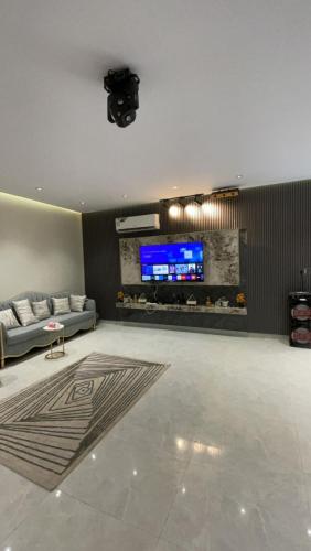 a living room with a couch and a tv on a wall at شالية الموج الازرق قسمين in Hafr Al Baten