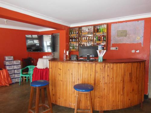 een bar met 2 krukken en een houten bar bij Psalms Motel in Entebbe