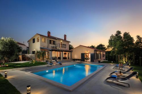 a swimming pool in a yard with chairs and a house at Villa PERLA VERDE in Labin