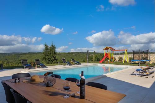 a table with a bottle of wine next to a pool at Villa PERLA VERDE in Labin