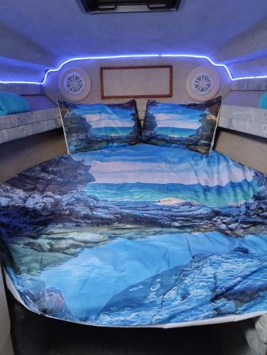 Una cama en la parte trasera de una caravana con una pintura. en Corazón Azul, en Puerto Calero