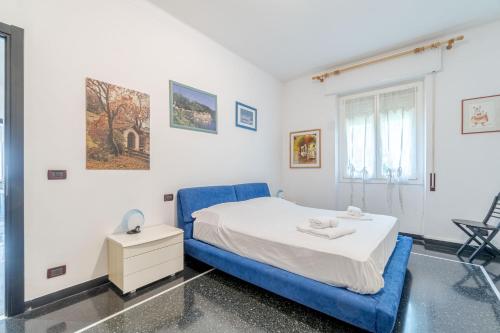 a white bedroom with a blue bed and a window at Castelletto Roomy & Functional Flat in Genoa