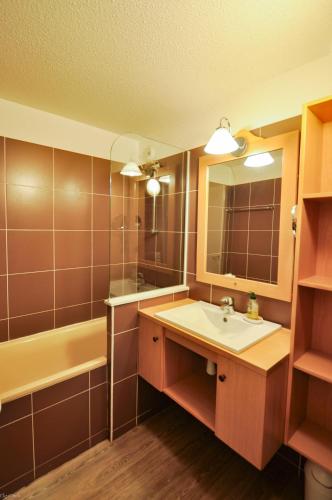 une salle de bain avec un lavabo, une baignoire et un miroir dans l'établissement Alpe Huez Quartier Les Bergers Appartement 5 personnes, à L'Alpe-d'Huez