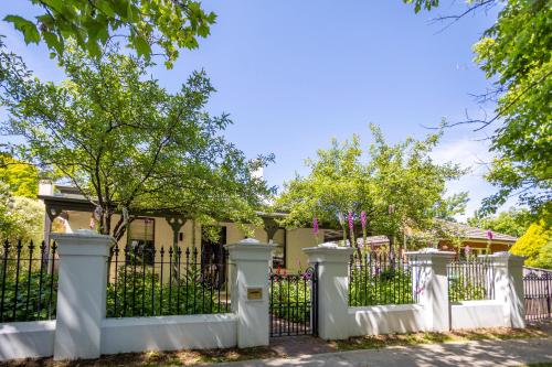 a white fence in front of a house with trees at Byng Street Garden Loft in Orange