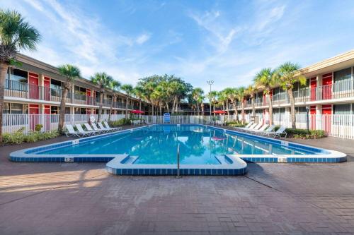 a swimming pool in front of a building with palm trees at Ramada by Wyndham Kissimmee Gateway - Free Theme Park Shuttle in Orlando