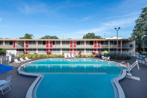 a hotel with a large pool in front of a building at Ramada by Wyndham Kissimmee Gateway - Free Theme Park Shuttle in Orlando