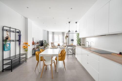 a kitchen with white cabinets and a table and chairs at Vilamercat in Sueca