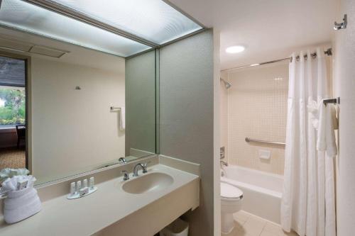 a bathroom with a sink and a toilet and a mirror at Ramada by Wyndham Kissimmee Gateway - Free Theme Park Shuttle in Orlando