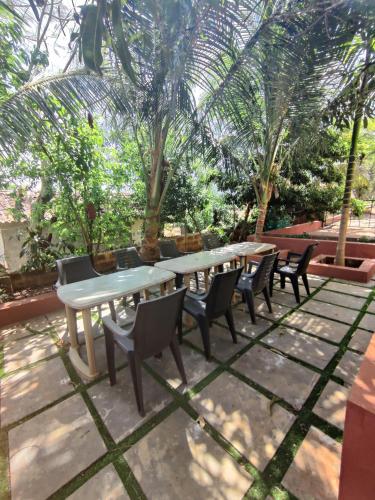 a table and chairs with trees in the background at Redstone House by Oxystays Hospitality in Ganpatipule