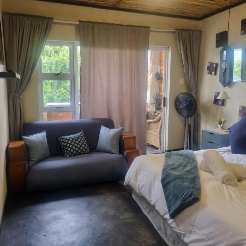 a bedroom with a couch and a bed and a window at Bedrock- Executive Self Catering Room in Cape Town
