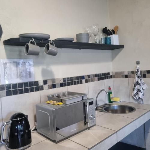 a kitchen counter with a sink and a microwave at Bedrock- Executive Self Catering Room in Cape Town