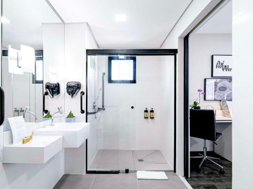 a white bathroom with a sink and a shower at Mercure Sao Paulo Ibirapuera Privilege in São Paulo