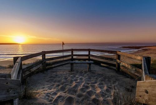 a sunset on the beach with a wooden boardwalk at Ramada Resort by Wyndham Phillip Island in Cowes
