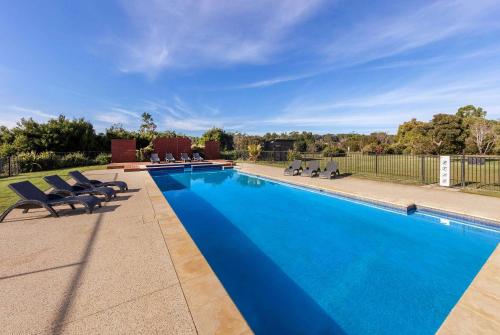 a swimming pool with chairs next to a fence at Ramada Resort by Wyndham Phillip Island in Cowes