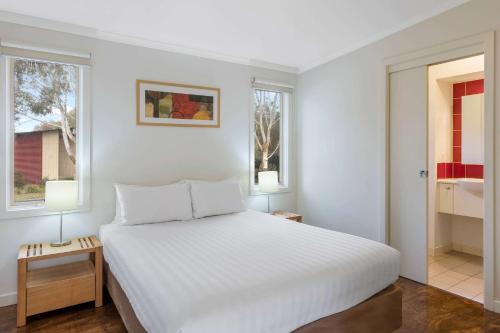 a bedroom with a white bed and two windows at Ramada Resort by Wyndham Phillip Island in Cowes