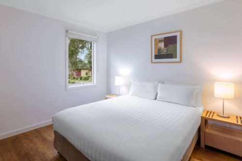 a bedroom with a white bed and two lamps at Ramada Resort by Wyndham Phillip Island in Cowes