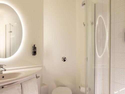 uma casa de banho branca com um chuveiro e um lavatório. em ibis Marseille Centre Euromed em Marselha