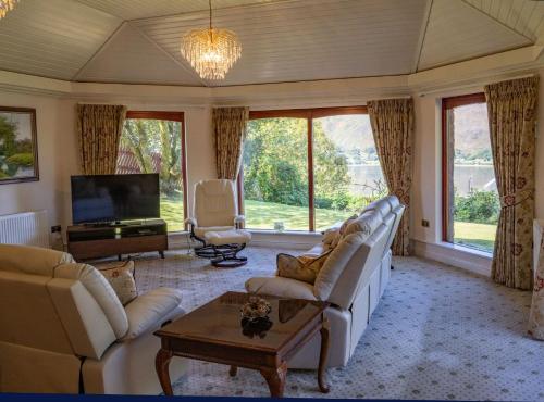 a living room with white furniture and large windows at Hillcrest in Fort William