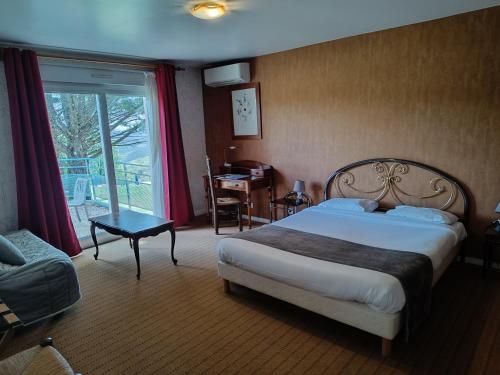 Schlafzimmer mit einem Bett, einem Schreibtisch und einem Fenster in der Unterkunft Logis Hotel La Bergerie in Saint-Pierre-Lafeuille