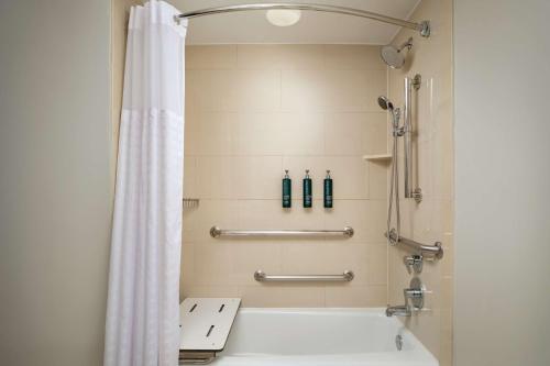 La salle de bains est pourvue d'une douche avec rideau de douche blanc. dans l'établissement Hilton New Orleans Riverside, à La Nouvelle-Orléans